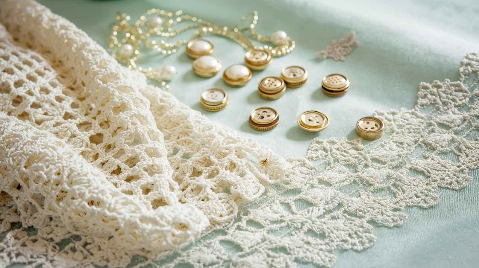 A collection of premium laces, pearl buttons, and embroidered borders for custom tailoring a Pakistani lawn suit.